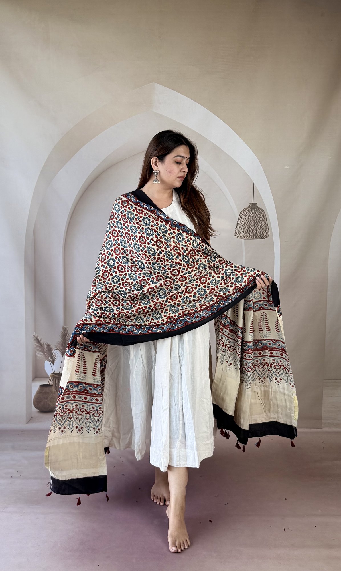 cream-ajrakh-modal silk-dupatta-geometric-lattice-2 Cream Ajrakh modal silk dupatta draped over both arms showing cypress motif palla and tassels